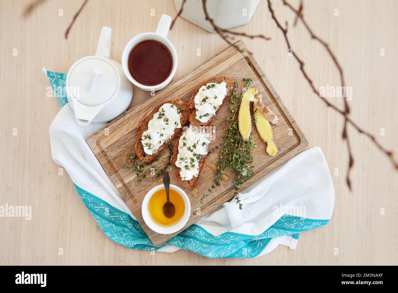 Plat Lay théière et tasse de thé ou de café, bruschetta au fromage, thym, gingembre et miel. Table de table en bois et serviettes en tissu. Onglet Banque D'Images