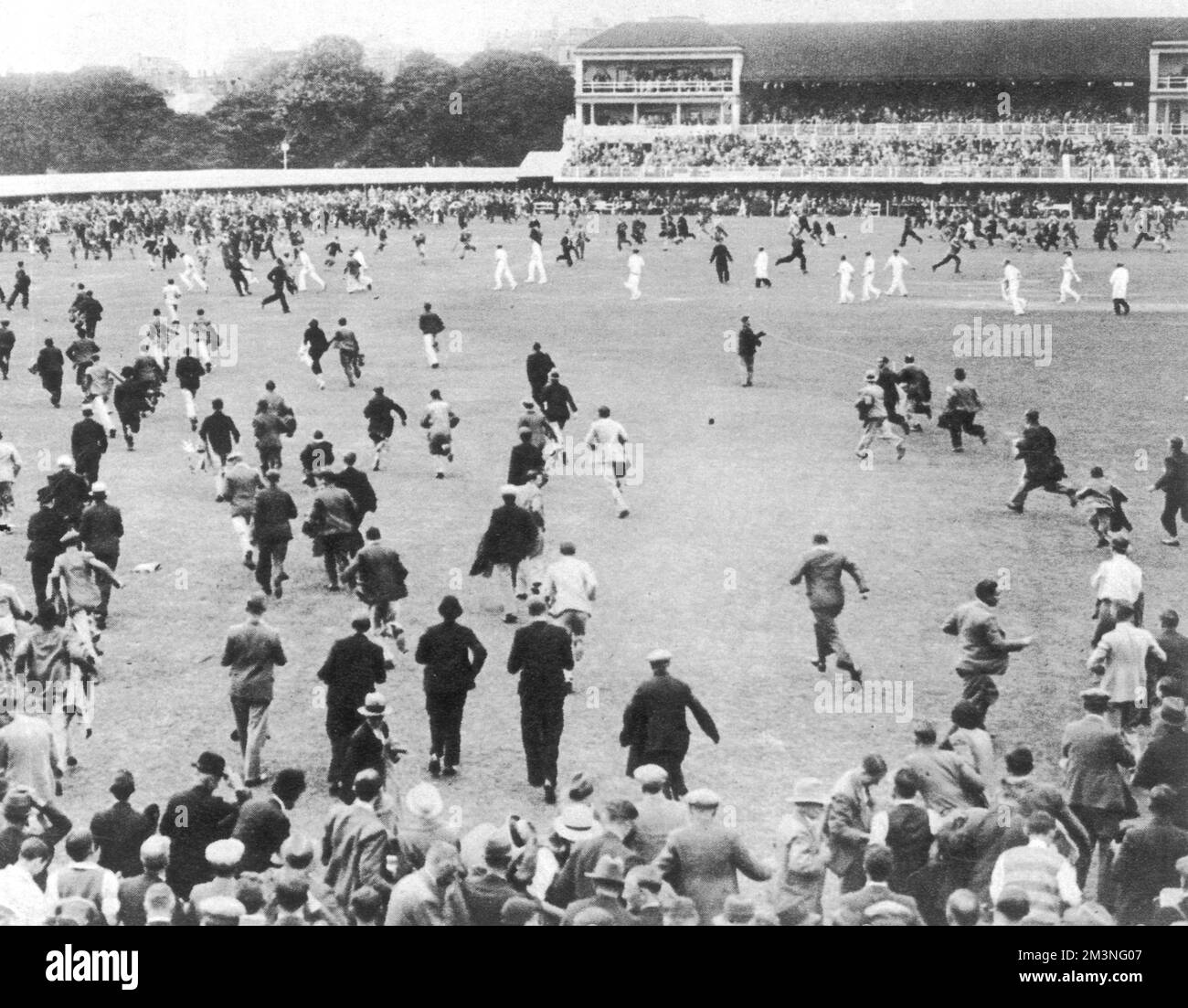 L'enthousiasme de la foule après la victoire de l'Angleterre : les spectateurs se faufilent sur le terrain, tandis que les joueurs font un trait pour le pavillon. L'Angleterre a battu l'Australie lors du deuxième match d'essai de Lor's le 25th juin par des gains et 38 courses, malgré les fortes pluies de week-end qui affectent le terrain. Date: 25 juin 1934 Banque D'Images