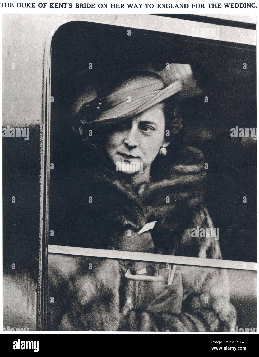 Princesse Marina de Grèce, épouse du prince George, duc de Kent à une fenêtre du train dans lequel elle a voyagé de Paris à Calais en route vers Londres pour son mariage à l'abbaye de Westminster le 29 novembre 1934. Toujours élégante, la future Duchesse porte une robe en crêpe rose beige, un manteau de trois quarts garni de renard, et un chapeau en soie beige cousue avec des plumes d'autruche beige et marron qui coulent sur le bord d'un côté. Comme le montre cette photo, elle a remplacé le manteau léger par un manteau de vison à certaines étapes de son voyage! Date: 1934 Banque D'Images