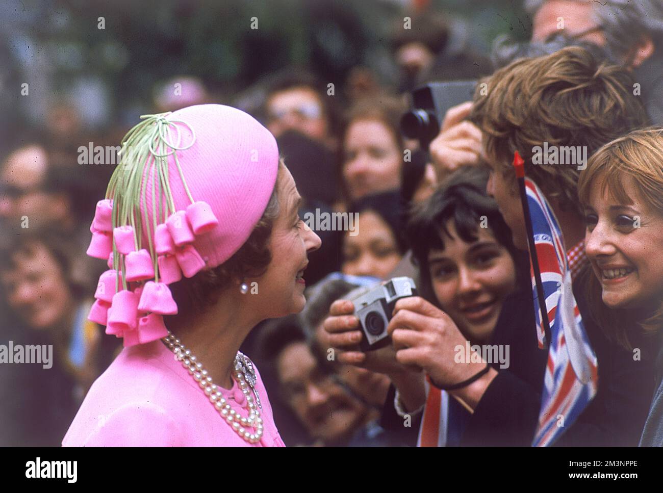 La reine Elizabeth II, une vision en sourires roses et discute avec des foules de bien-enthousiastes lors d'une promenade royale à Londres pour célébrer son Jubilé d'argent en 1977. Banque D'Images