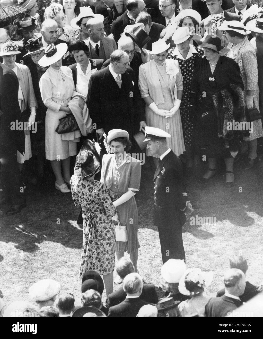 Le prince Elizabeth (reine Elizabeth II) et son lieutenant Philip Mountbatten discutant avec des invités lors d'une fête dans le jardin sur le terrain de Buckingham Palace en juillet 1947, peu après l'annonce de leur engagement. Date: 1947 Banque D'Images