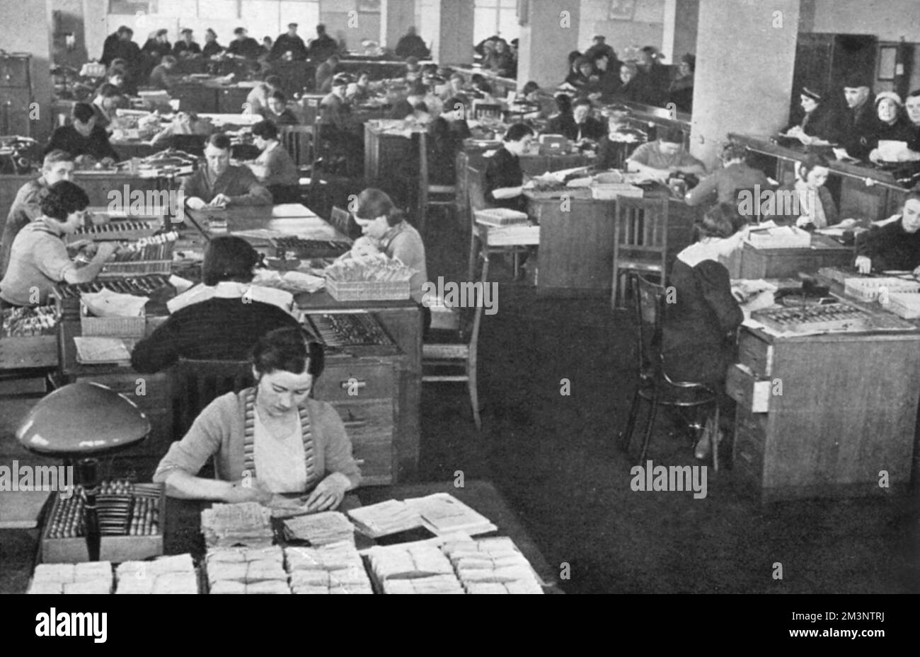 Enregistrer les dépôts de travailleurs soviétiques dans la Banque d'Etat de l'URSS en 1939. À droite, les déposants peuvent être vus au comptoir en attendant leur tour tandis que les greffiers hommes et femmes sont occupés par des services bancaires. Date: 1939 Banque D'Images
