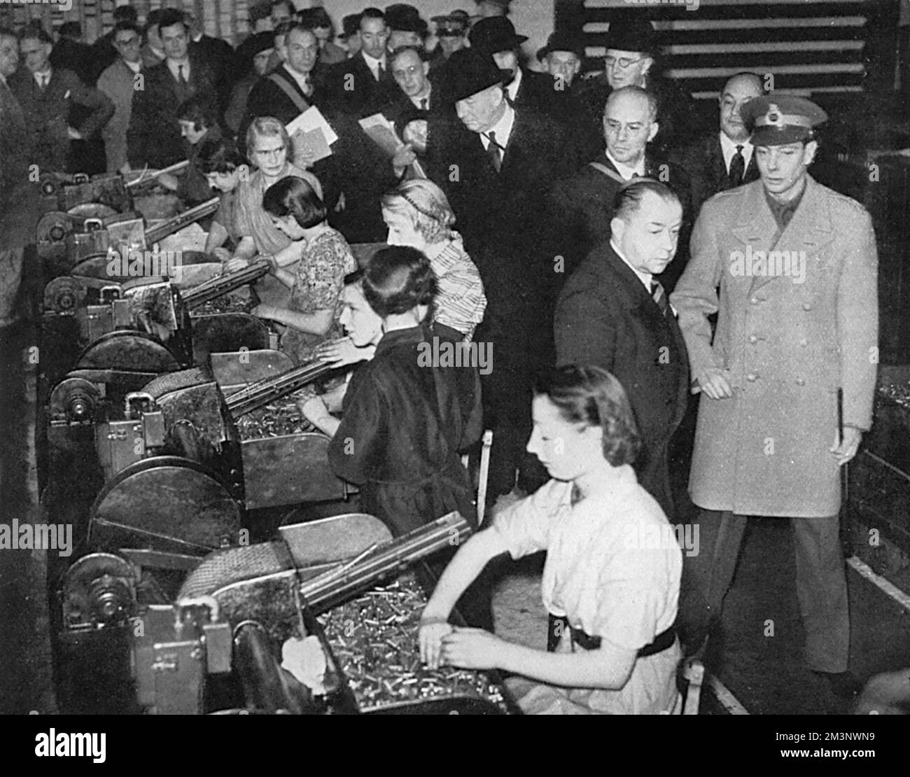 Le roi George VI se voit offrir une visite d'inspection d'une usine de l'Ordnance royale et de voir de première main l'immense effort mis en place pour produire des armes, dans ce cas-ci des armes anti-aériennes et anti-chars. L'image montre le roi regardant certaines des travailleuses dans l'usine de tri des munitions. Date: 1939 Banque D'Images