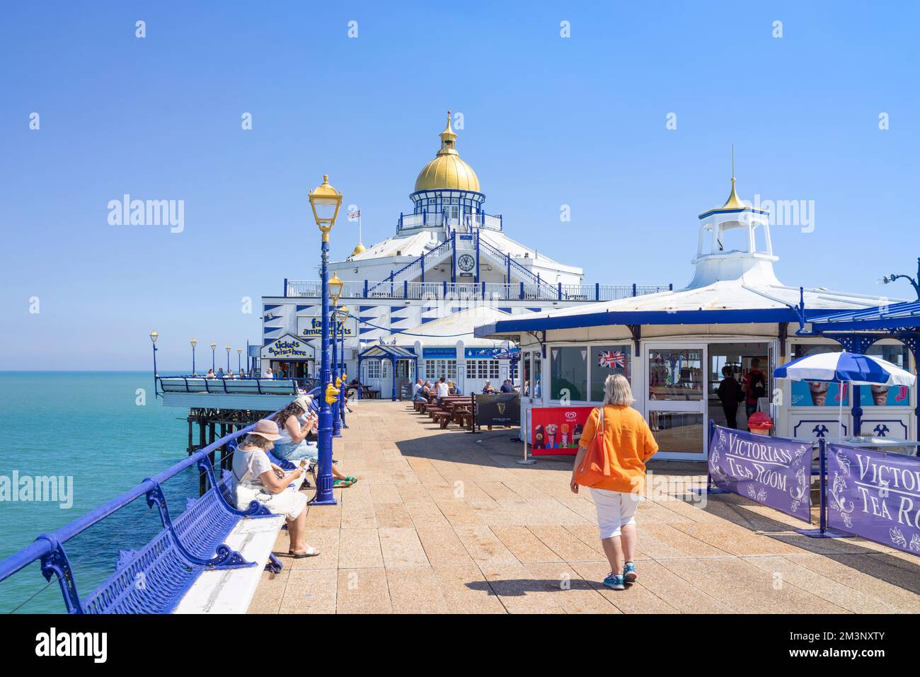 Eastbourne East Sussex une femme marchant sur Eastbourne Pier et d'autres se sont assis sur des bancs sur Eastbourne Pier Eastbourne East Sussex England UK GB Europe Banque D'Images