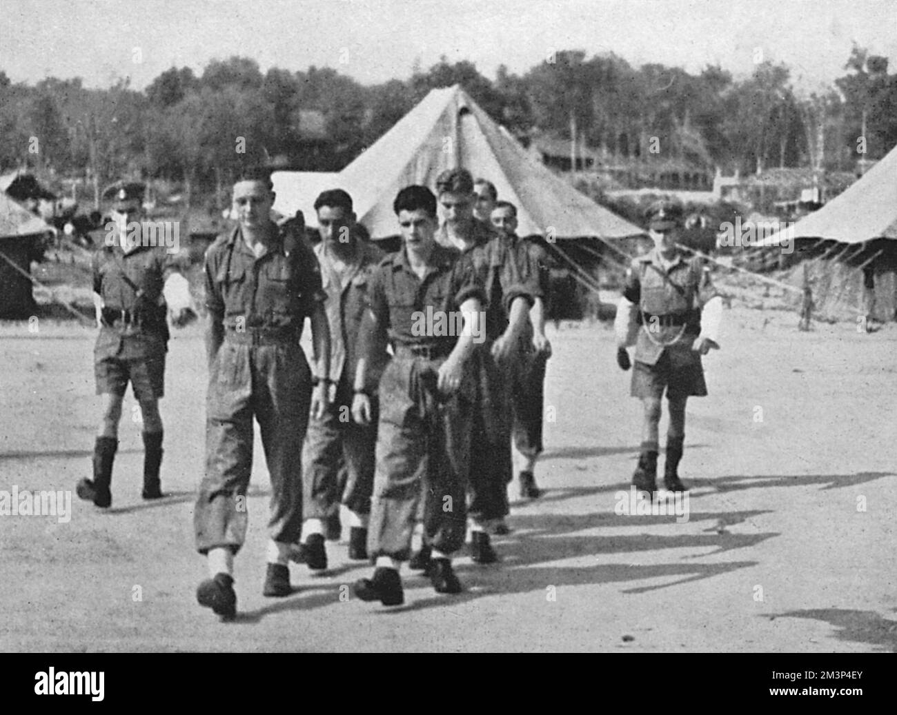 Certains des soldats accusés du Régiment de parachutistes du 13th Bataillon dans l'affaire Muar sont escortés par la police militaire à travers l'aérodrome de Kluang pendant la cour martiale. En mai 1946, au camp de Muar à Malaya, plus de 250 soldats ont refusé d'obéir aux ordres et ont été plus tard accusés de mutinerie. Trois ont été acquittés, huit condamnés à cinq ans de servitude pénale et les deux autres à deux ans d'emprisonnement. Lorsque des nouvelles sont parvenues au Royaume-Uni, deux jours après la détermination de la peine, le juge-avocat général a annulé les peines en raison d'irrégularités qui ont rendu le procès insatisfaisant. Date: 1946 Banque D'Images