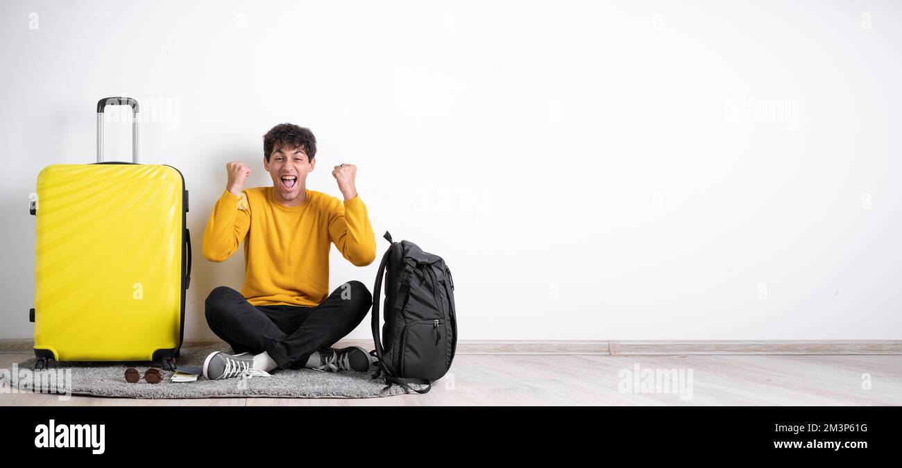 Jeune voyageur gars avec valise de joie succès poing mains génial isolé sur fond blanc de couleur. Bannière Banque D'Images