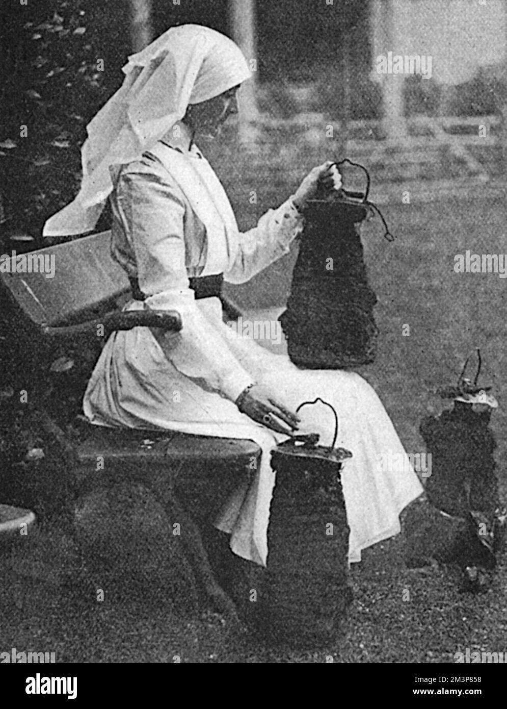 Lady Stradbroke, anciennement Helena Fraser et épouse de George Rous, 3rd comte de Stradbroke, photographiée en uniforme d'infirmière à la maison familiale de Henham Hall à Suffolk, en contemplant les bombes larguées par des avions allemands en avril 1915. La maison a été transformée en hôpital militaire pendant la première Guerre mondiale et a reçu des convois de soldats blessés directement de France, qui ont été transmis à la Croix-Rouge une fois suffisamment bien. Lady Stradbroke a pris la seule charge comme matron et a efficacement surintenté l'hôpital. Henham Hall a été démoli en 1953. Date: 1915 Banque D'Images