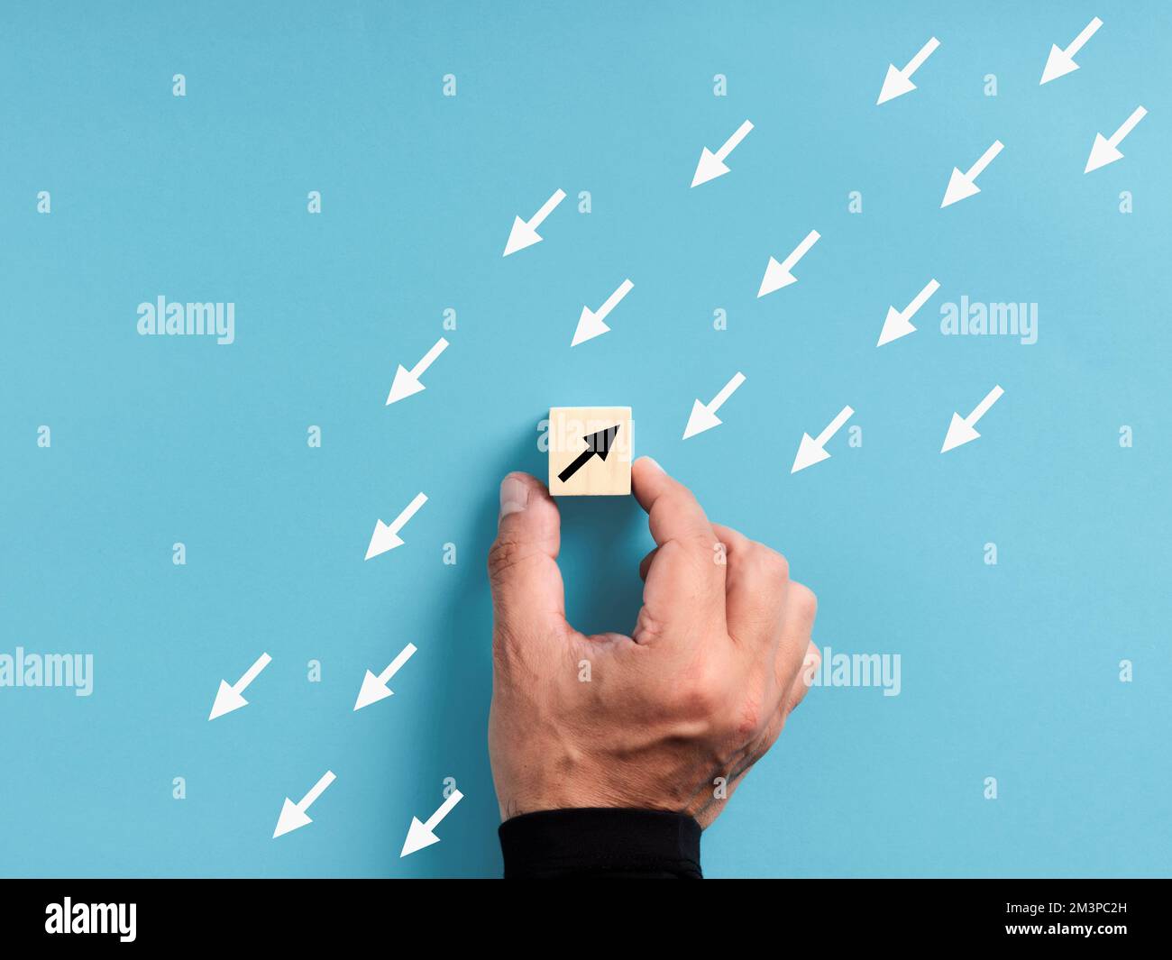 Unique, pensez différent, individualité. Nagez contre le ruisseau et sortez de la foule. Main mâle plaçant un bloc de bois avec un point d'intérêt opposé Banque D'Images