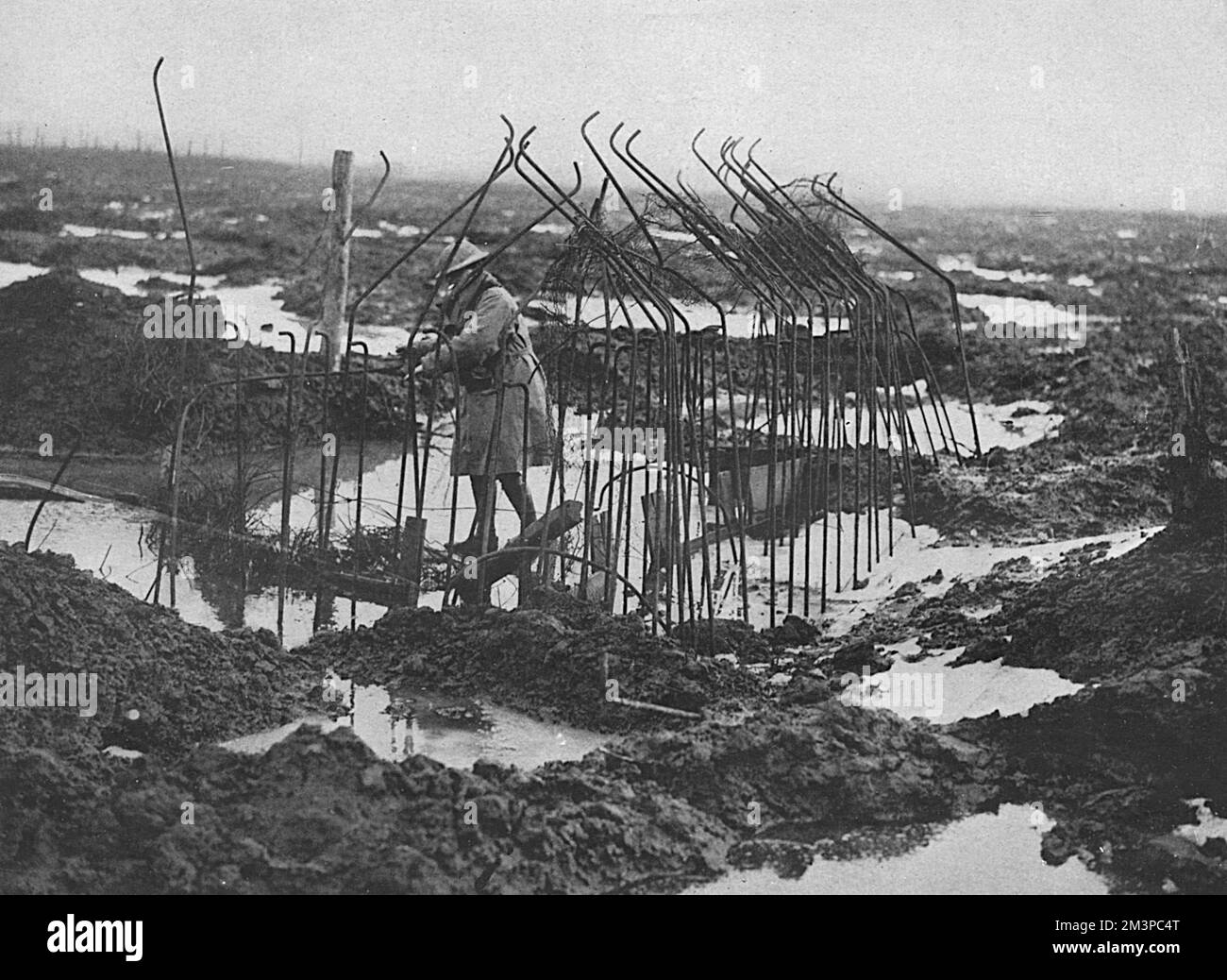 Un paysage boueux et inondé en Flandre avec un soldat britannique qui inspecte le squelette d'une boîte à pilules non achevée. L'image illustre les conditions déplorables et le terrain impossible. Date: 1918 Banque D'Images