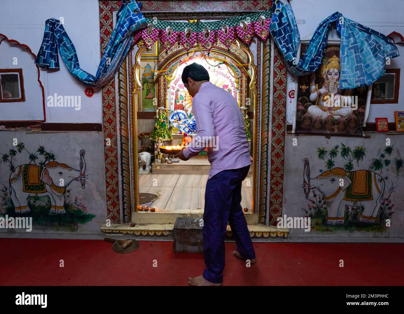 Homme indien offrant des bougies dans un temple pour Diwali, Rajasthan, Jaipur, Inde Banque D'Images