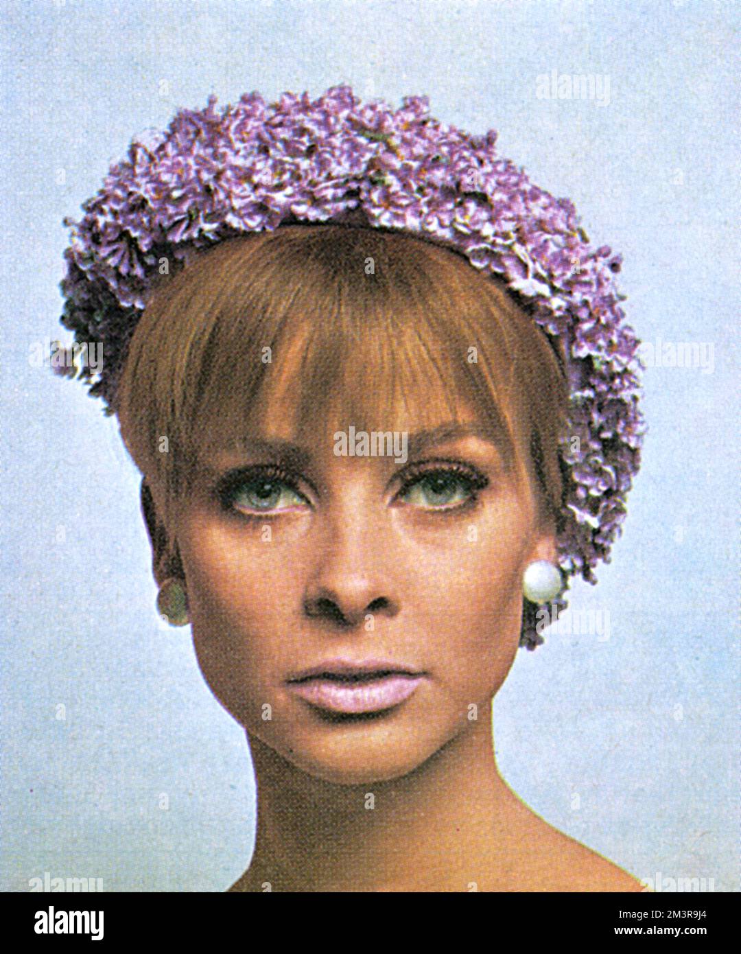 Modèle portant un béret de Pâques recouvert de fleurs lilas. Porté avec maquillage par facteur max. Date: 1966 Banque D'Images