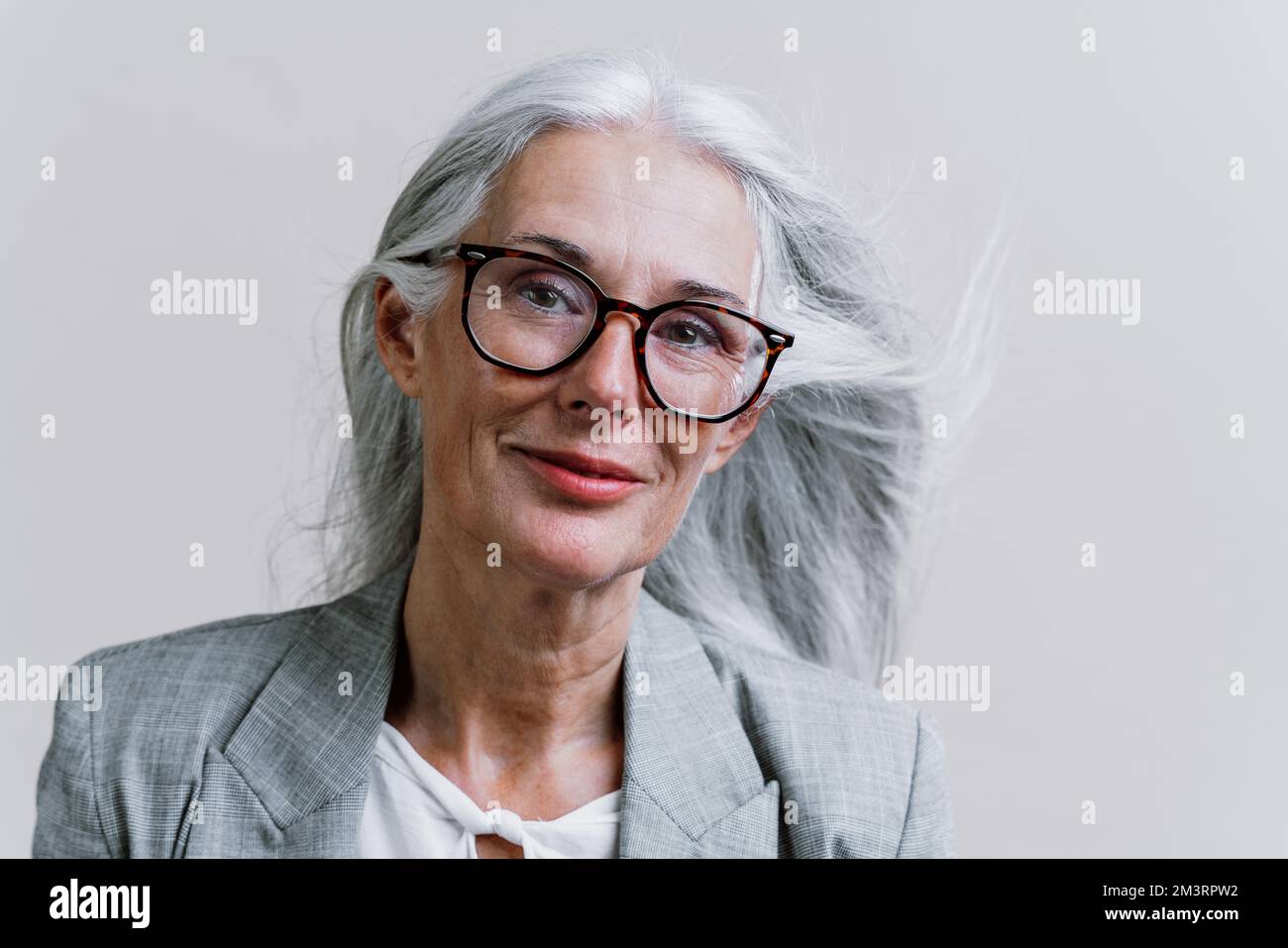 Belle femme senior posant sur une séance de photo d'entreprise. Femme d'affaires avec costume élégant sur fond coloré en studio. Banque D'Images