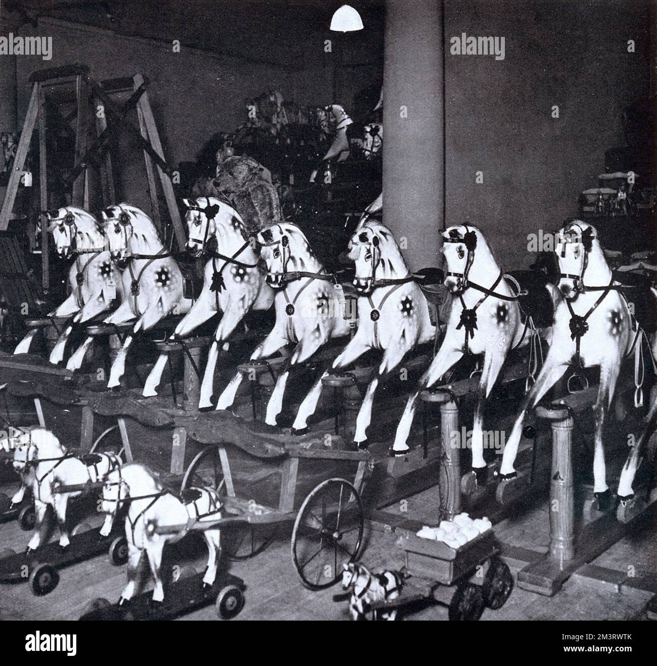 Une exposition uniforme de chevaux à bascule en bois et de petits chevaux en peluche sur roues dans le rayon des jouets Harrods, Noël 1922. Date: 1922 Banque D'Images