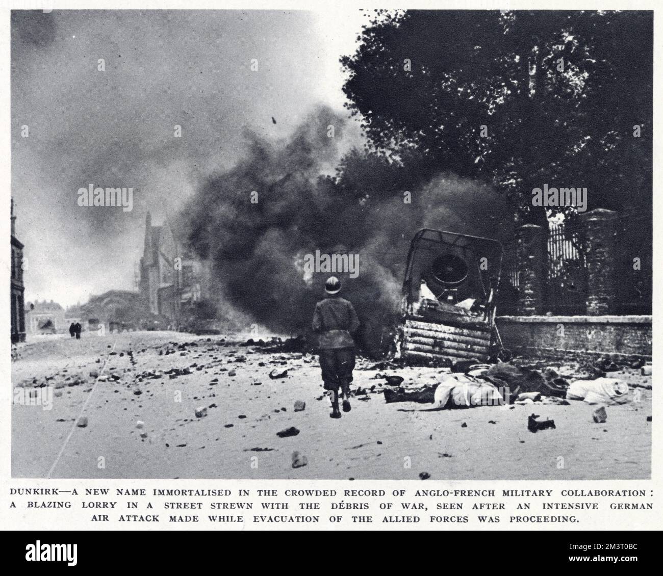 Scène de rue lors de l'évacuation de Dunkerque, dans le nord de la France, montrant un camion en feu avec de la fumée noire qui s'envenime et des débris qui entament le sol après une attaque aérienne allemande intense. Date: 1940 Banque D'Images