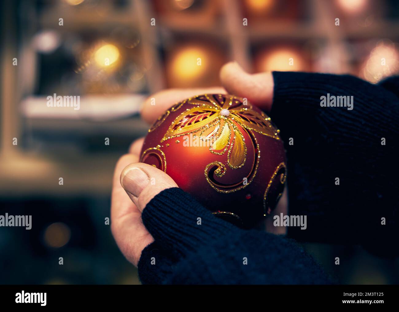 Femme tenant une boule de Noël rouge brillant dans ses mains sur un arrière-plan flou Banque D'Images