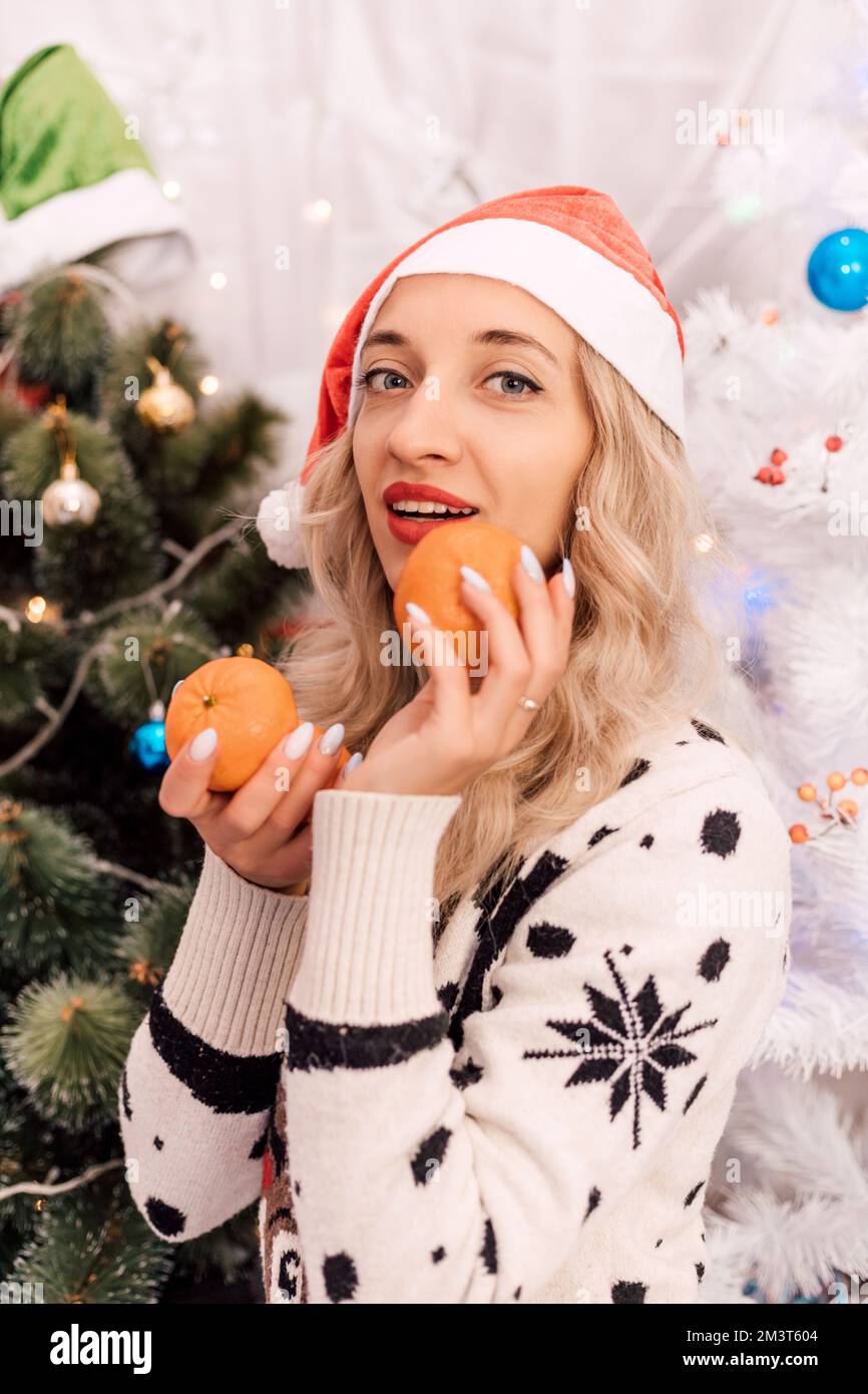 Une femme dans un chandail tient des tangerines dans ses mains. Noël. La nourriture du nouvel an Banque D'Images