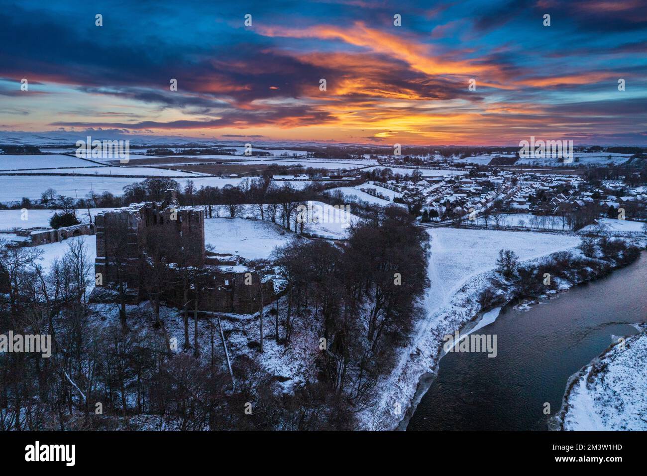 Le château de Norham gardait la frontière écossaise au-dessus de la rivière Tweed pendant les couchers de soleil sur un paysage d'hiver. Norham, Northumberland, Angleterre, Royaume-Uni Banque D'Images