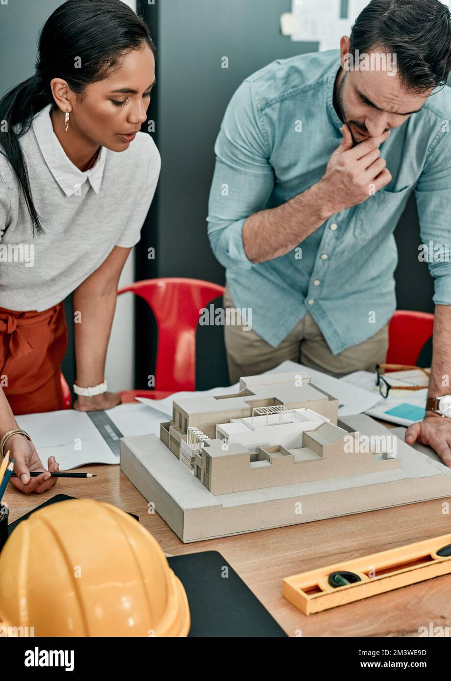 Faire couler leur jus créatif. deux architectes travaillent ensemble sur un modèle d'échelle d'un bâtiment dans un bureau. Banque D'Images