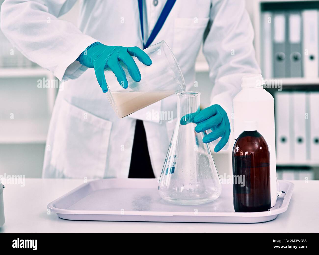 Mise en place de son expérience... une scientifique féminine méconnaissable transférant un liquide d'un bécher à une fiole conique tout en travaillant dans un laboratoire. Banque D'Images