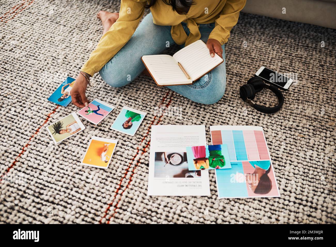 Je pense que cette image sera belle sur mon blog. une femme d'affaires méconnue assise sur le sol de son salon et passant par les polarids pour elle Banque D'Images