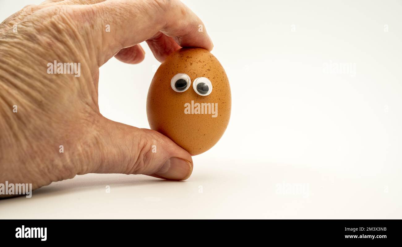 homme personne chef cuisinier tenant un œuf de poule avec des yeux de bonne humeur isolés sur un fond blanc Banque D'Images