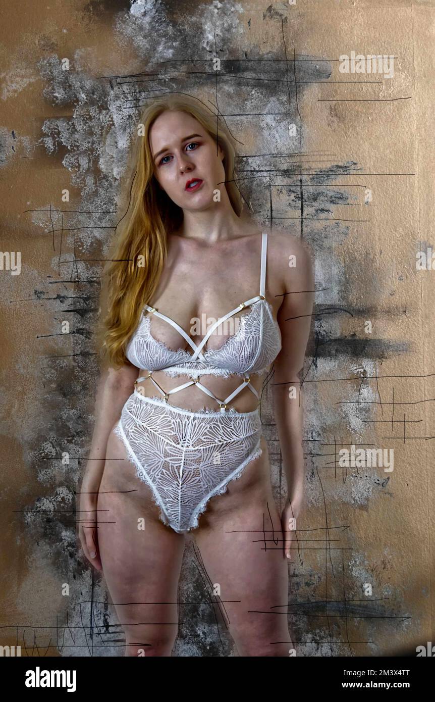 Une jeune femme aux cheveux rouges portant de la lingerie blanche et un fond peint blanc, noir et or. Banque D'Images