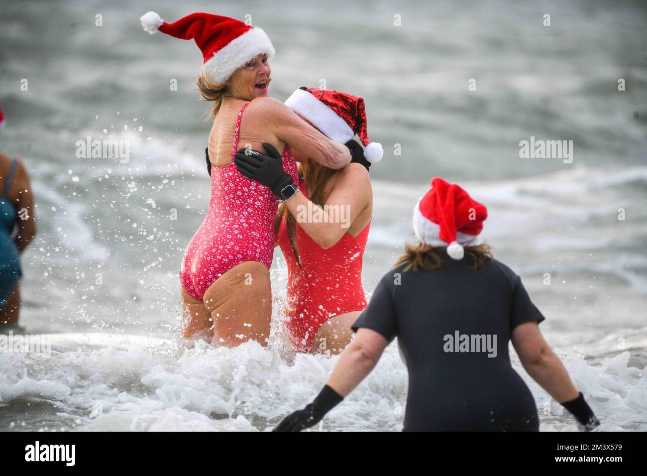 Les amateurs de fonds bravent les eaux glaciales de la baie de Langland, Swansea, lors de l'événement annuel de Santa Surf qui a lieu à la plage de Gower chaque année pour recueillir de l'argent pour les surfeurs contre Sewerage et aider les surfeurs locaux à entrer dans l'esprit de Noël. Banque D'Images