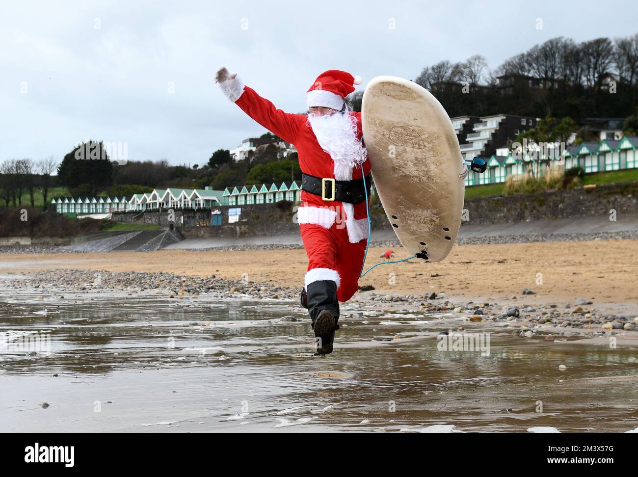 Le surfeur local, Andy Parkinson, a photographié se dirigeant vers les eaux glaciales de Langland Bay, Swansea, lors de l'événement annuel de Santa Surf qui a lieu à la plage de Gower chaque année pour recueillir de l'argent pour les surfeurs contre Sewerage et aider les surfeurs à entrer dans l'esprit de Noël. Banque D'Images
