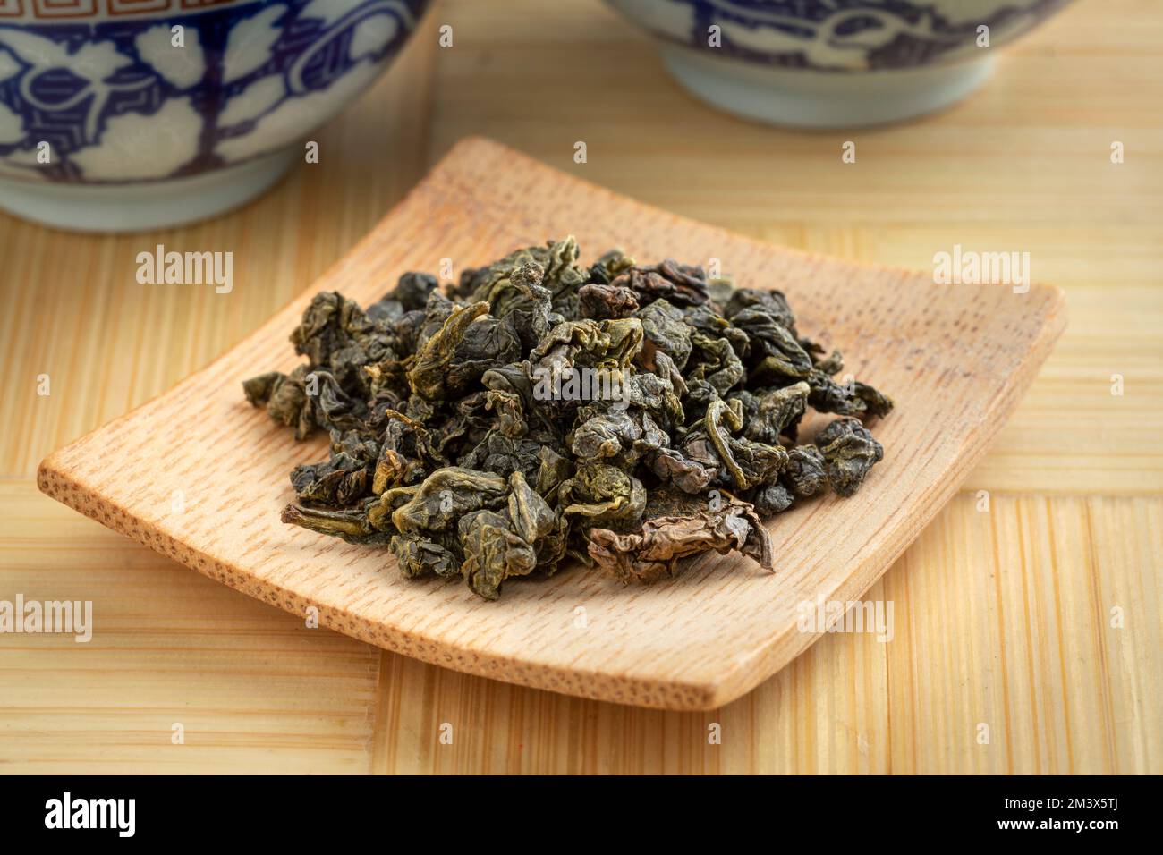 Plaque de bambou avec chinois Ti Kuan Yin thé oolong bio feuilles de thé séchées gros plan Banque D'Images