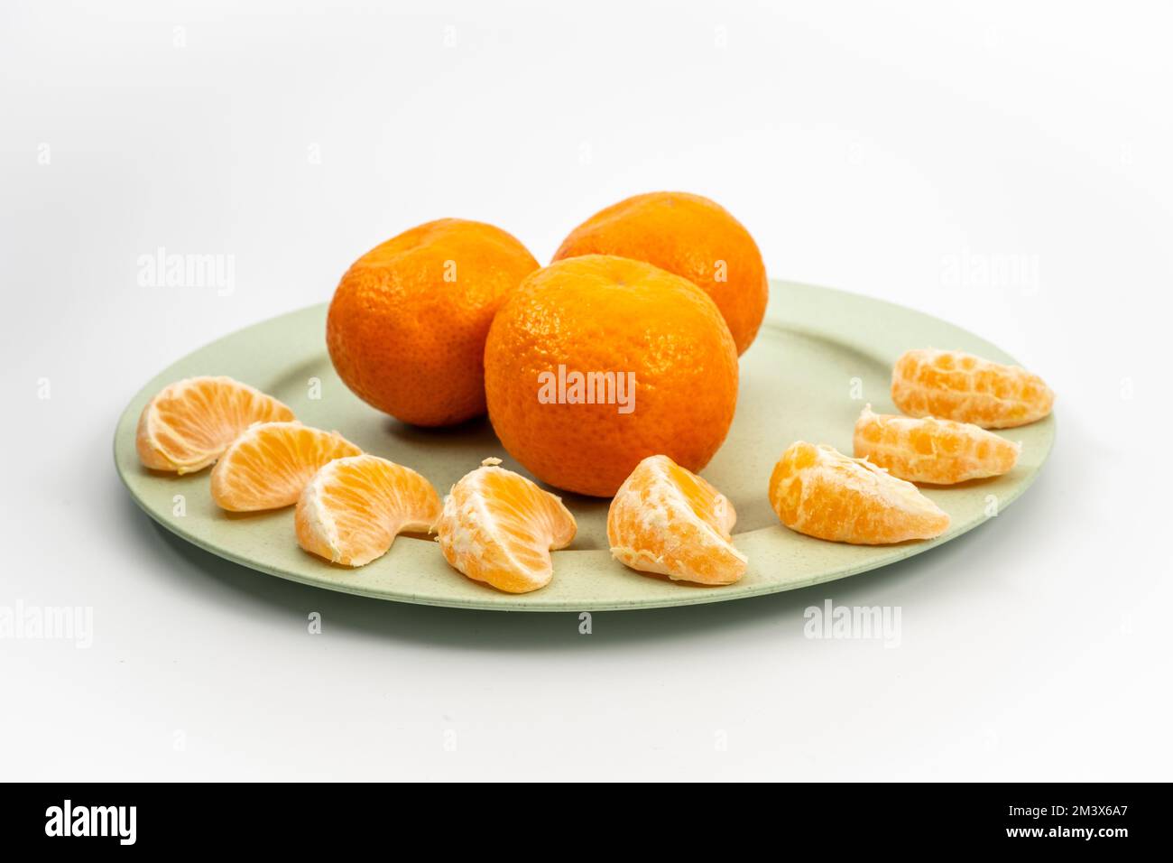 quelques satsumas tangerines avec des segments orange nettoyés disposés sur une plaque verte Banque D'Images