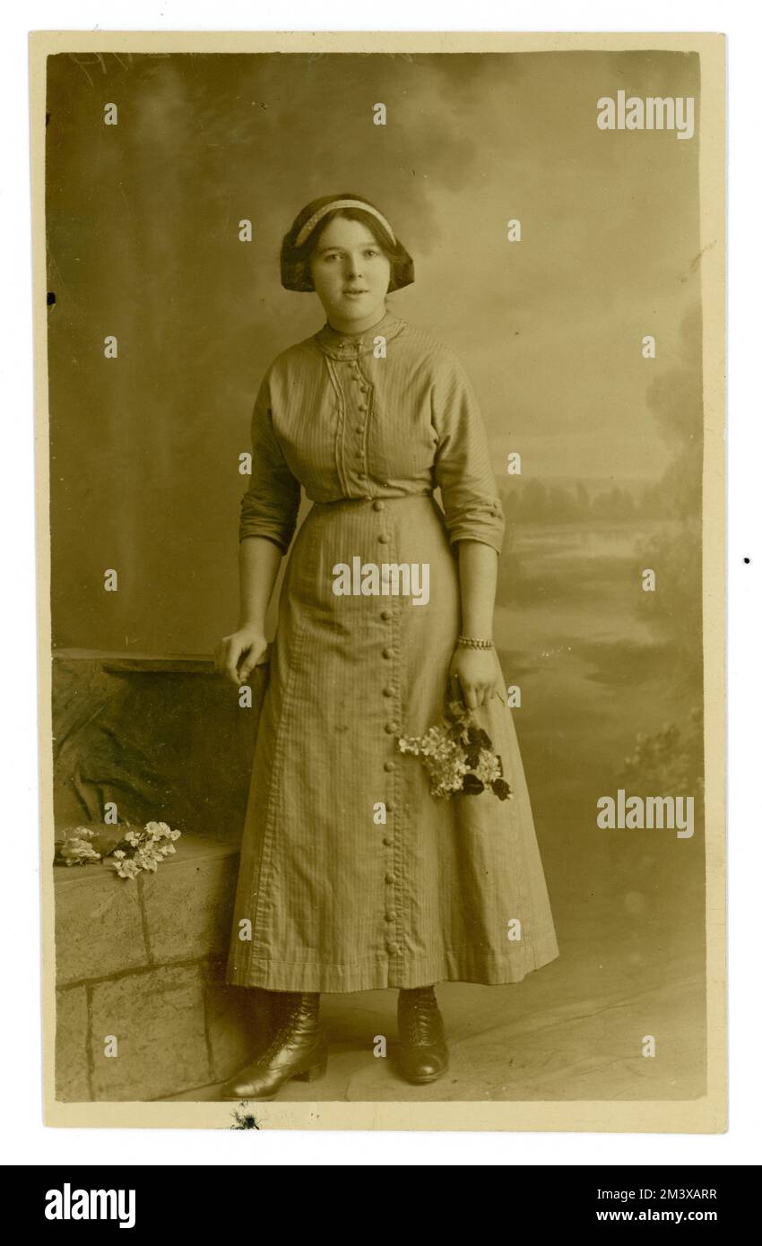 Original de WW1 ans portrait carte postale de fin de l'adolescence belle fille / jeune femme, portant un chemisier et une jupe longue, la hemline juste au-dessus de sa cheville, ses cheveux semble être attaché dans un arc à l'arrière, peut-être sa première photo adulte. U.K, vers 1915. Banque D'Images