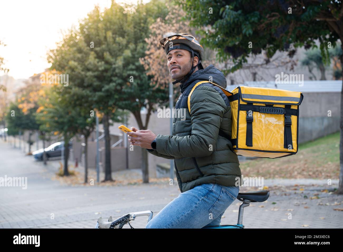 Concept de livraison de nourriture. Jeune conducteur noir avec sac à dos style smartphone dans la ville Banque D'Images