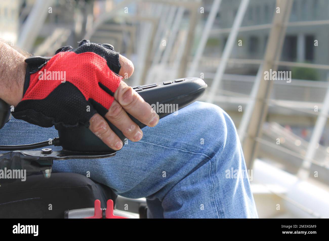 Main gantée avec blessures d'une personne handicapée en fauteuil roulant sur un pont Banque D'Images