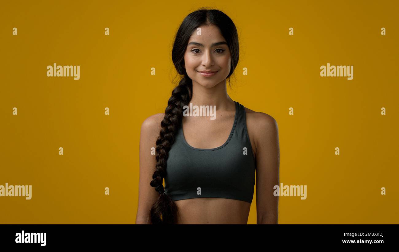 Ethnique 20s femme indienne sport dame souriant multiracial forte fille mince entraîneur sportif coureur de yoga posant dans jaune studio athlète femelle regardant Banque D'Images