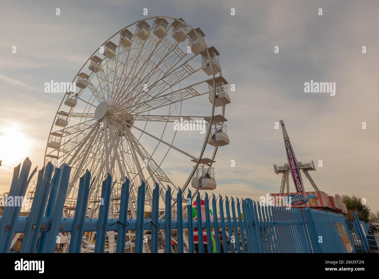 Southend on Sea, Royaume-Uni. 17 décembre 2022. Une grande roue avec des gondoles fermées et un manège vertical appelé Power Surge se tiennent derrière une clôture métallique bleue sous un ciel partiellement nuageux. Un après-midi froid sur le front de mer avec des températures autour de 2C ne tient pas les amateurs de sensations fortes loin de Adventure Island. Penelope Barritt/Alamy Live News Banque D'Images