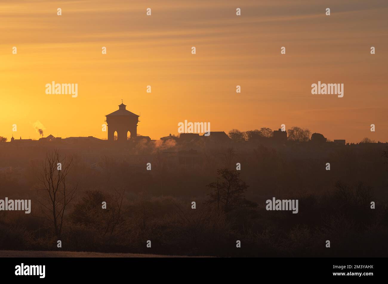 Vue sur la tour d'eau Jumbo de Colchester depuis une distance. Silhouettes des bâtiments au soleil du matin. Lever le soleil sur Colchester, Essex. Banque D'Images