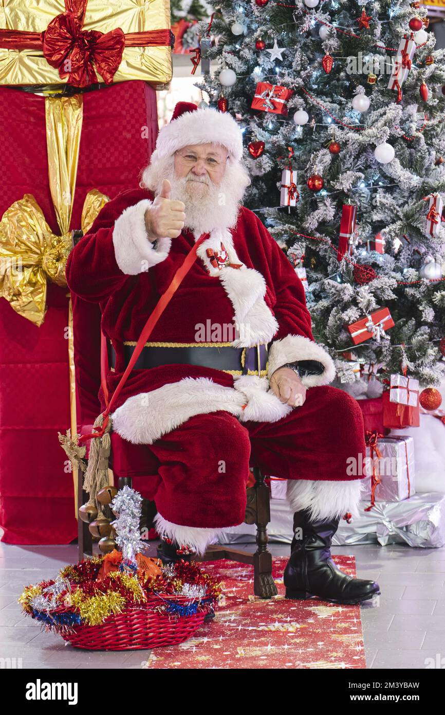 Le Père Noël par l'arbre de Noël assis avec de grands cadeaux. Milan, Italie - décembre 2022 Banque D'Images