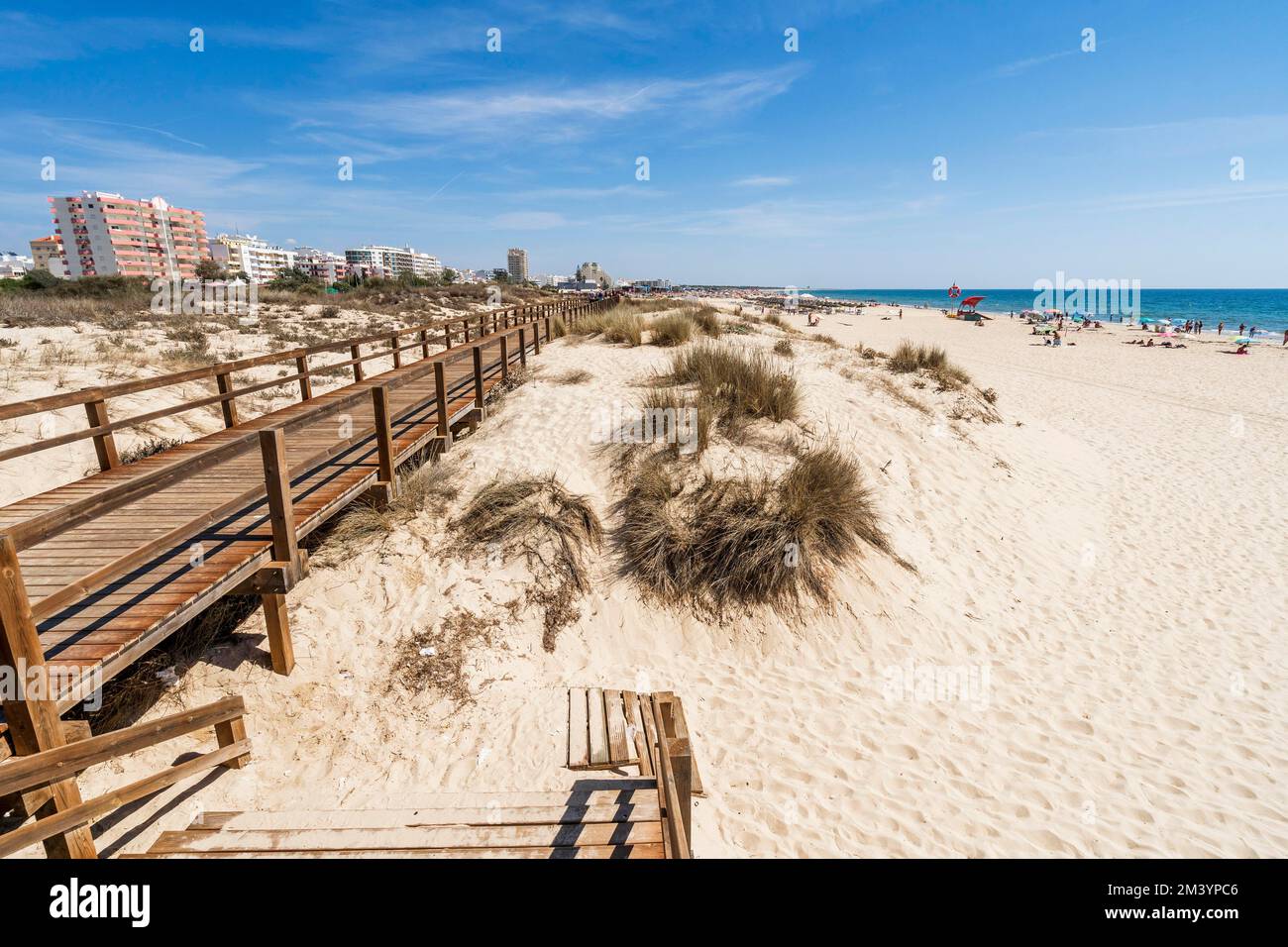 Large plage de sable avec ponts en bois le long des dunes de Monte Gordo, Algarve, Portugal Banque D'Images