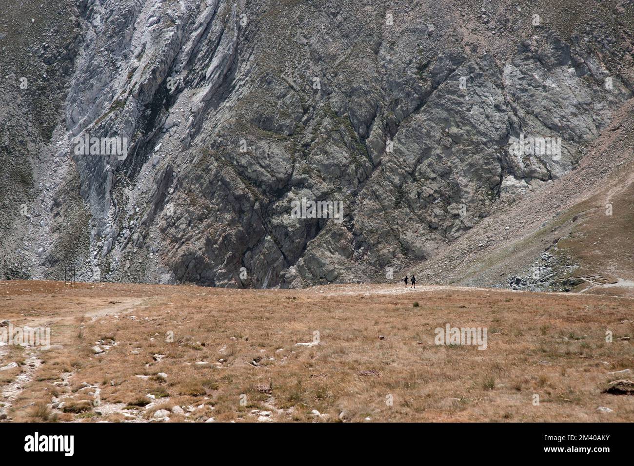 Une vue sur les personnes marchant devant un grand mur d'une haute montagne dans un paysage dans les Pyrénées près du pic Bastitents Banque D'Images