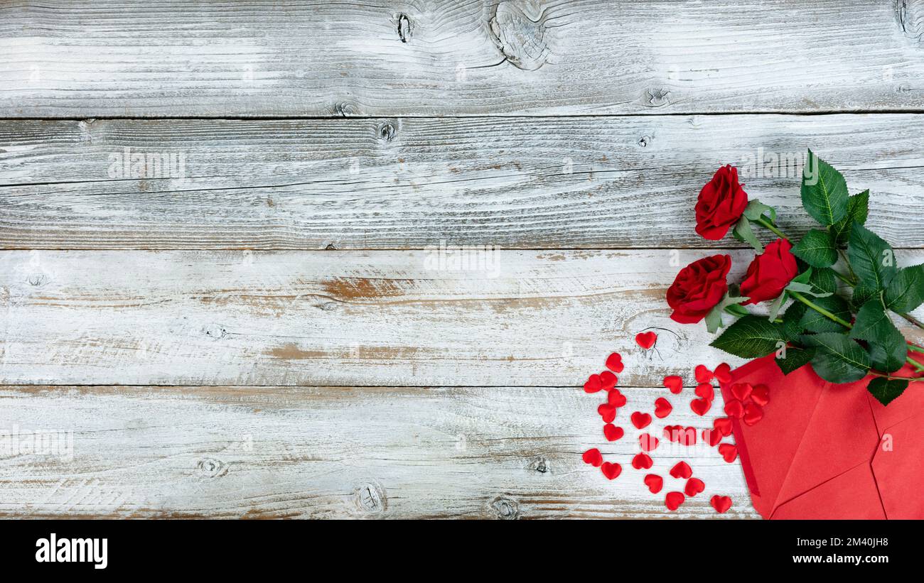 Concept de salutation de Saint-Valentin avec enveloppe, coeurs rouges et roses de fleur sur fond de bois rustique blanc Banque D'Images