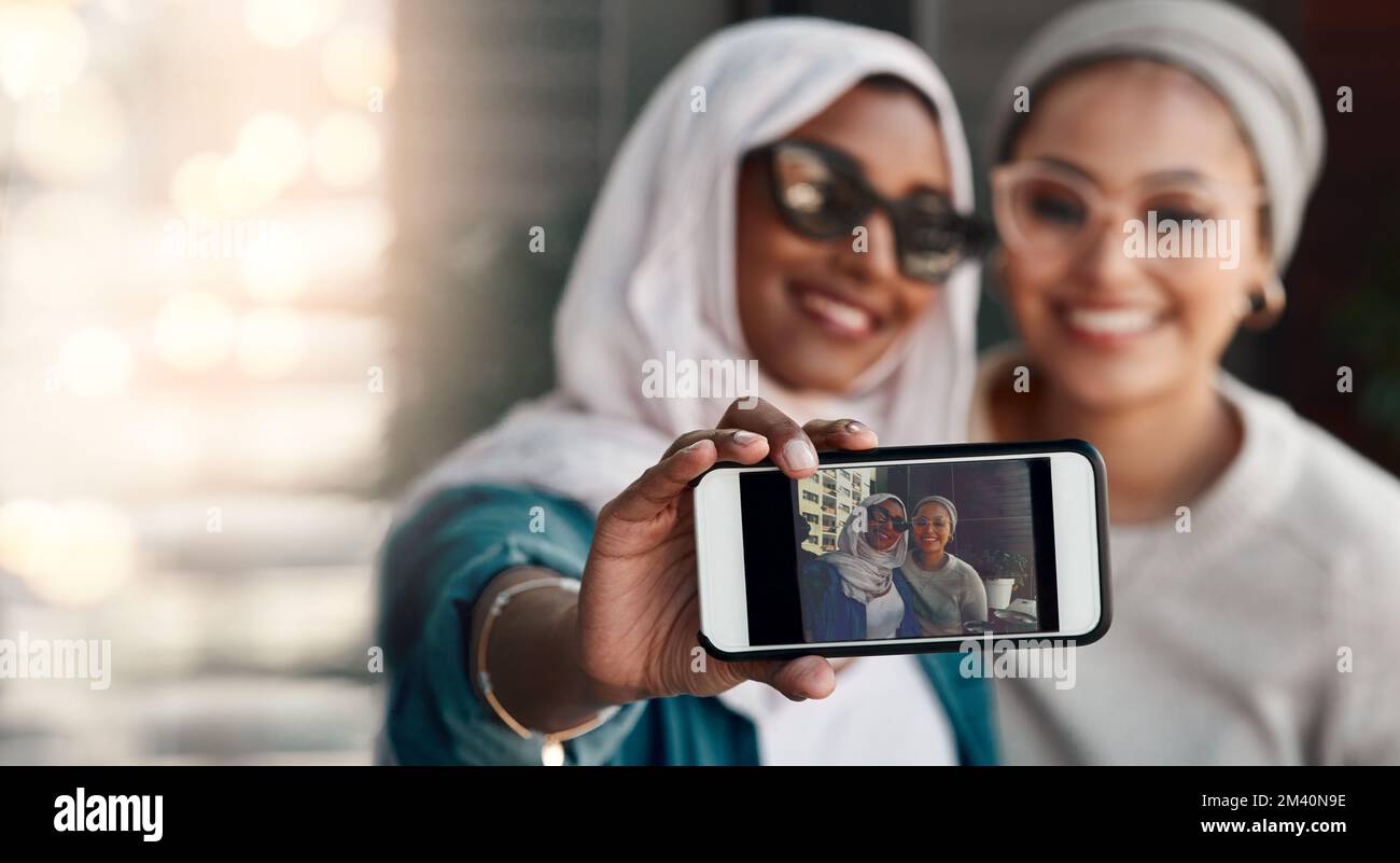 Photogénique est ce qu'ils sont. Un petit cliché de deux jeunes amies affectueuses emportant un selfie dans un café tout en étant vêtues de hijab. Banque D'Images