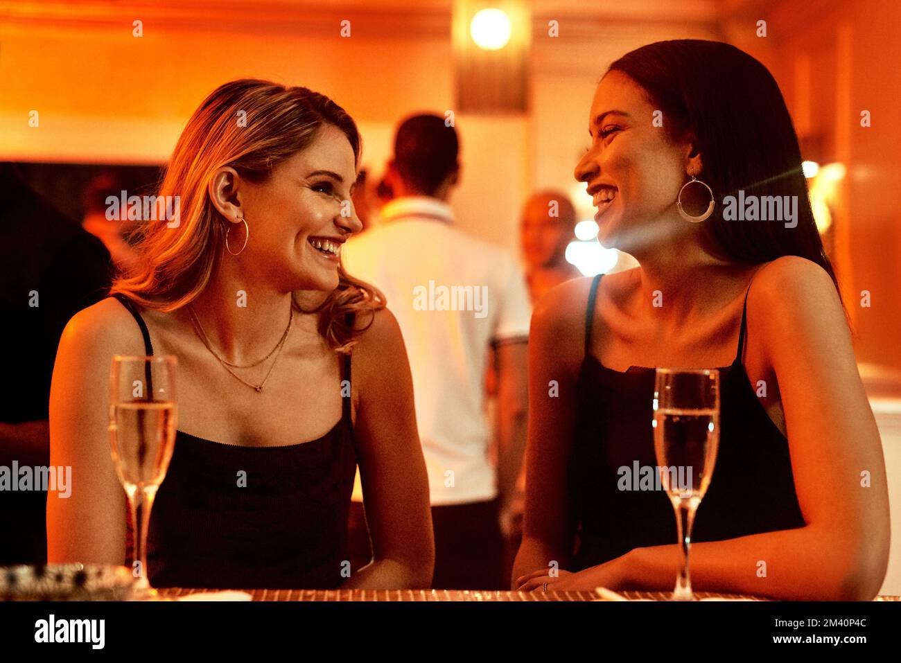 Ils ont toujours beaucoup de banneurs ensemble. deux jeunes femmes gaies bavardent tout en prenant un verre dans un bar le soir. Banque D'Images