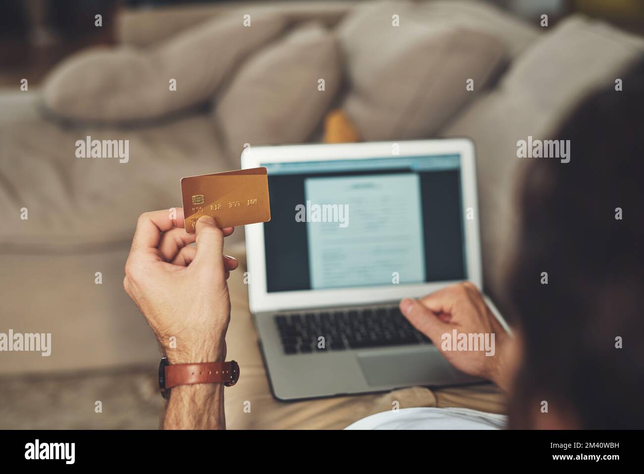 C'est ce que j'appelle le pouvoir d'achat. un homme méconnaissable utilisant son ordinateur portable et sa carte de crédit tout en se relaxant sur un canapé à la maison. Banque D'Images