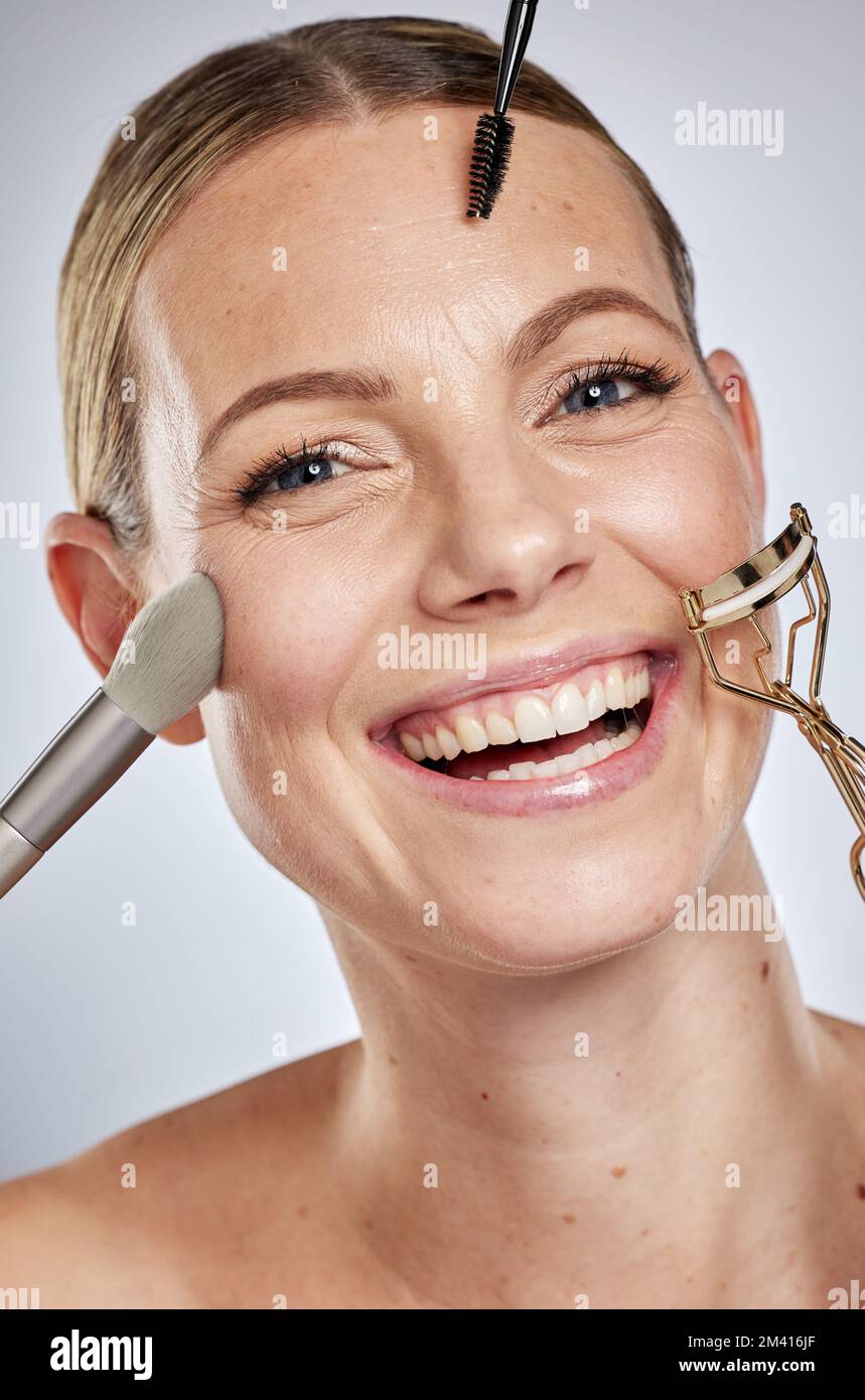 Beauté, portrait ou femme avec un pinceau pour maquillage, rouleau et eyeliner pour soin du visage routine de soin de la peau en studio. Bien-être, visage ou fille heureuse Banque D'Images