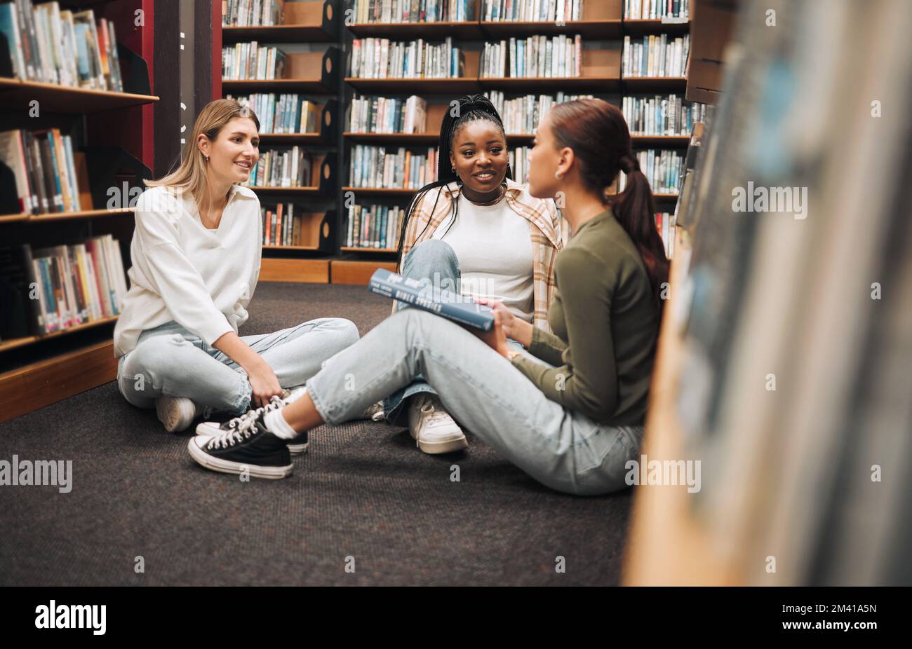 Bibliothèque, livre et groupe de femmes lisant pour l'éducation, la recherche et le savoir à l'université. Discussion, bourses et étudiantes étudiant pour Banque D'Images