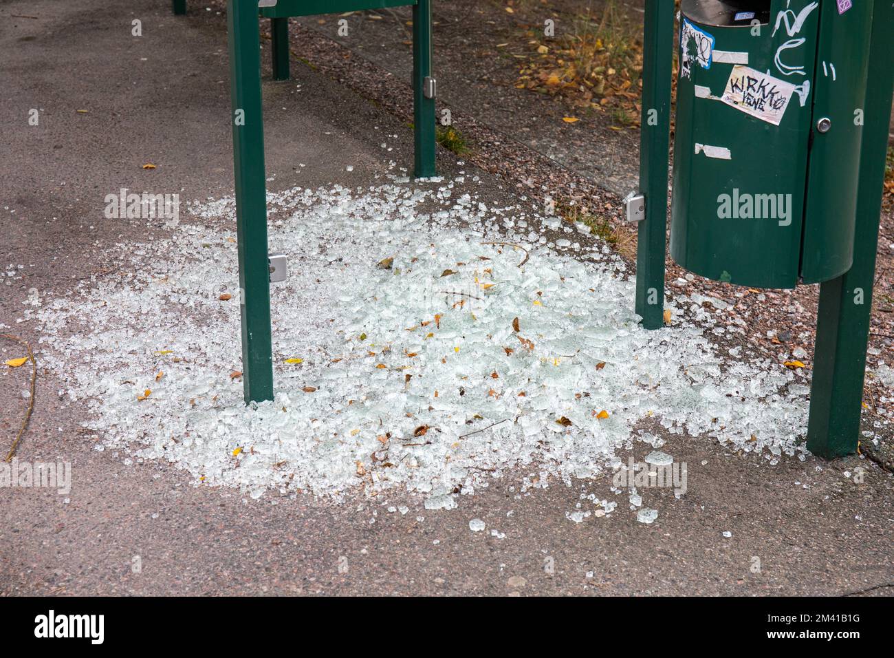 Des éclats au sol autour d'un abri d'arrêt d'autobus vandalisé dans le district de Vähä-Meilahti à Helsinki, en Finlande Banque D'Images