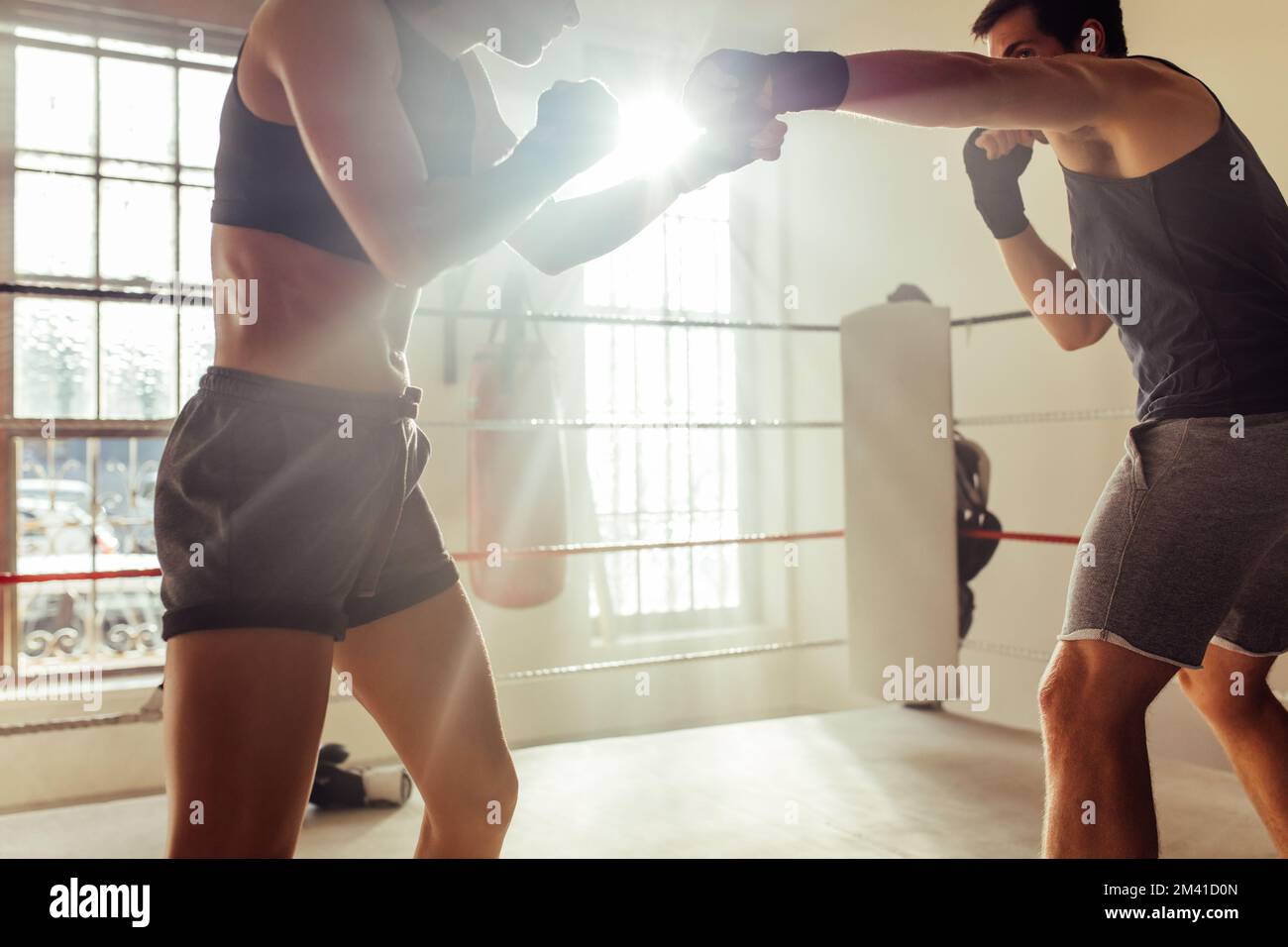 Deux pugilistes se battant dans un ring de boxe. Deux jeunes boxeurs ayant un match pendant une séance d'entraînement dans un gymnase de boxe. Banque D'Images