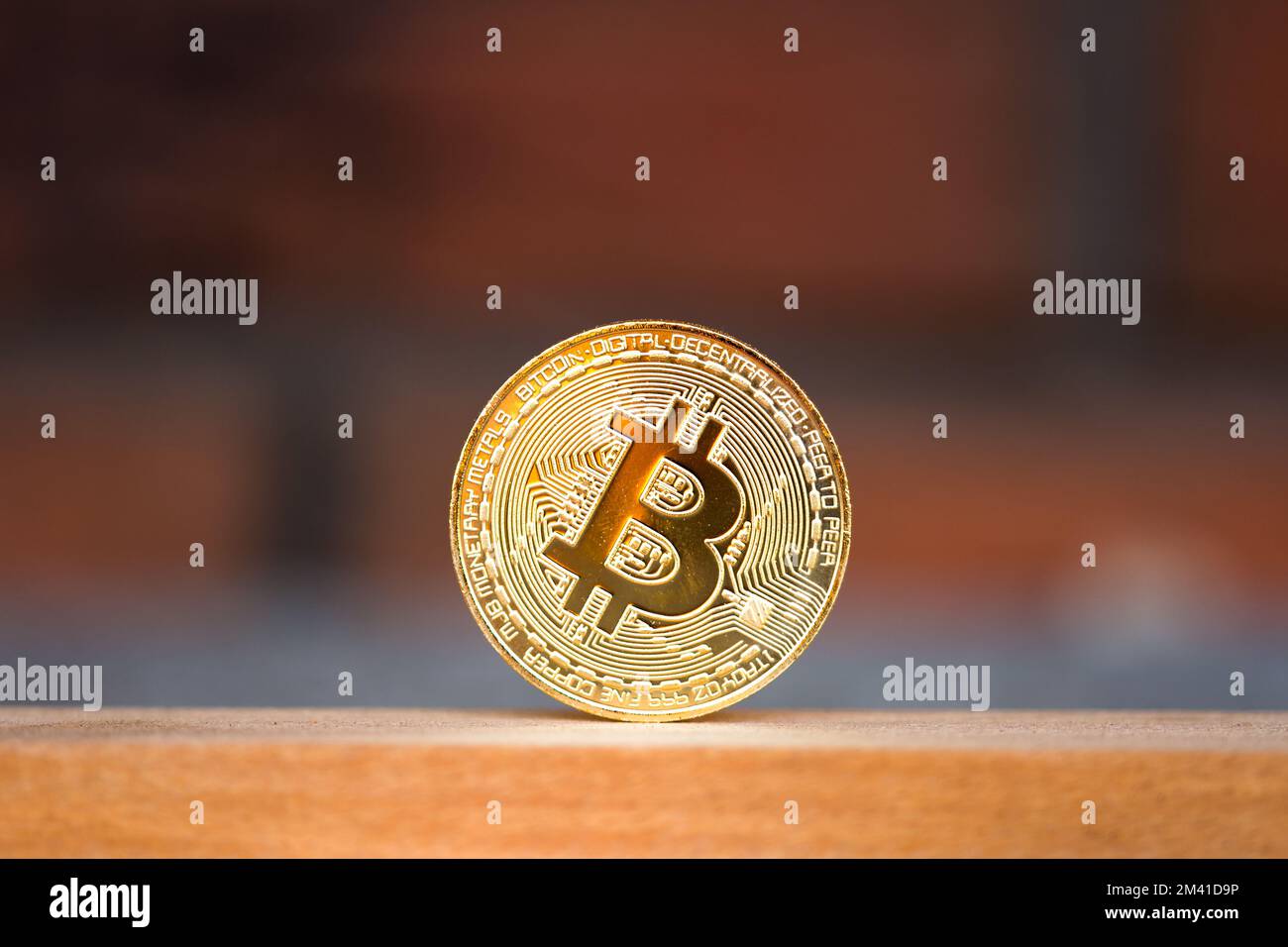 Pièce de monnaie en bitcoin or placée sur le bureau en bois avec fond rouge brique. Symbole de crypto-monnaie virtuelle Banque D'Images