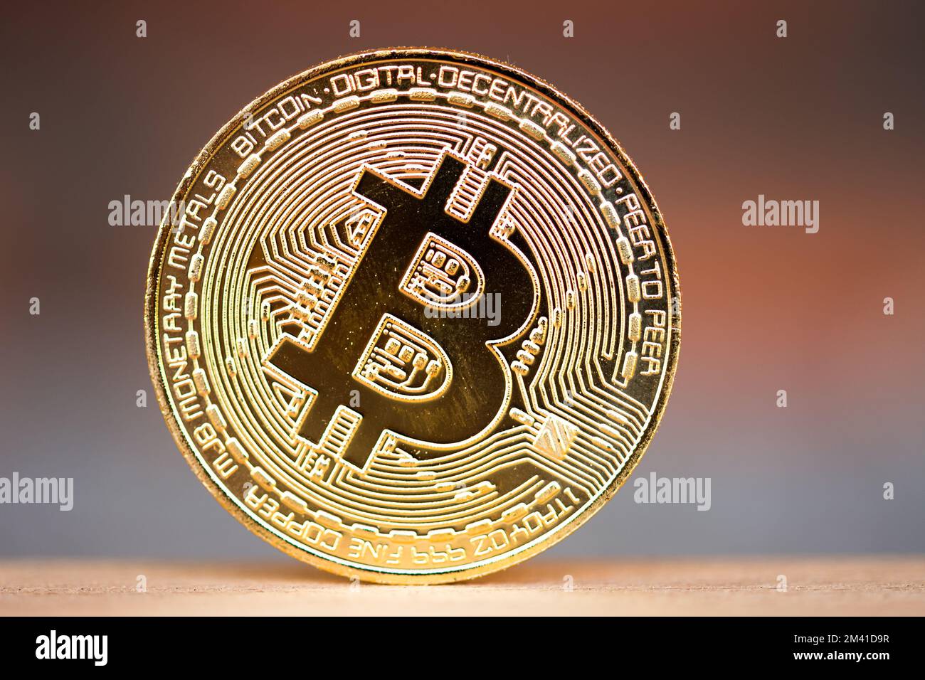 Pièce de monnaie en bitcoin or placée sur le bureau en bois avec fond rouge brique. Symbole de crypto-monnaie virtuelle Banque D'Images