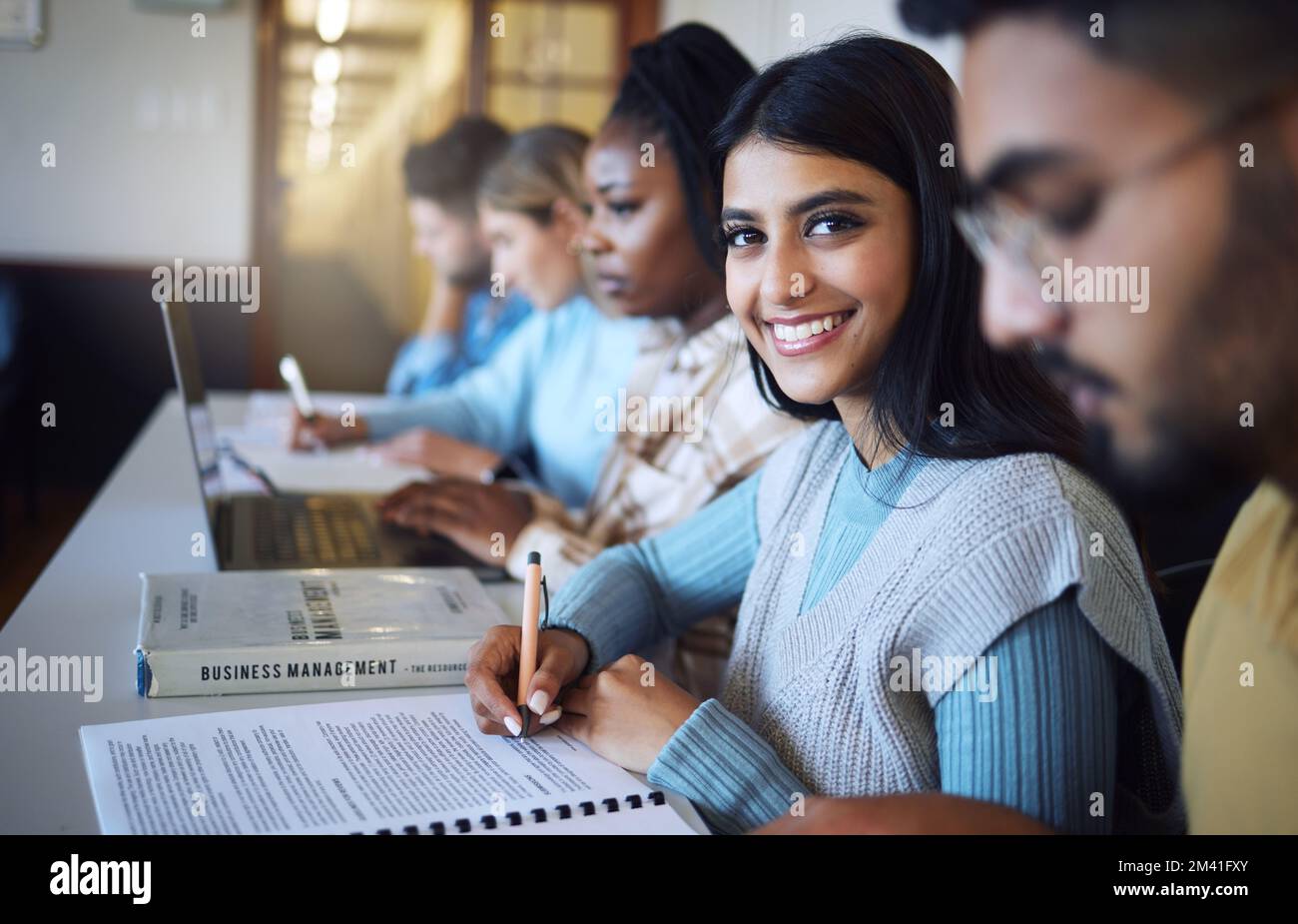 L'étudiant de l'université écrit des notes pour la gestion des affaires en classe, cours et campus. Portrait, jeune fille indienne et étudiant à l'université heureux pour Banque D'Images